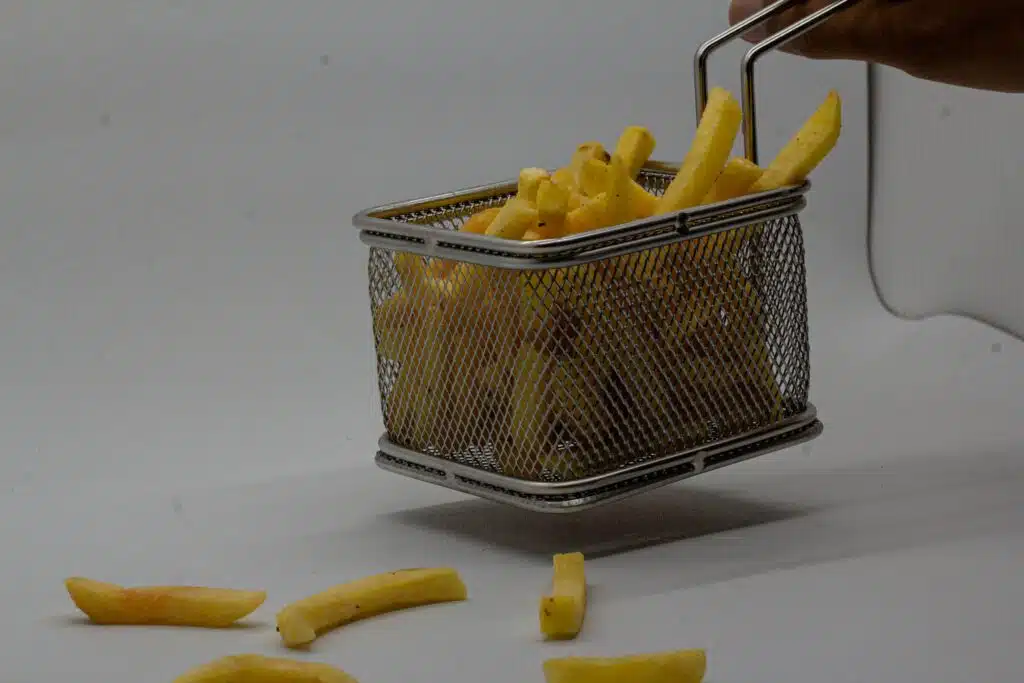 a basket full of french fries with a person picking them